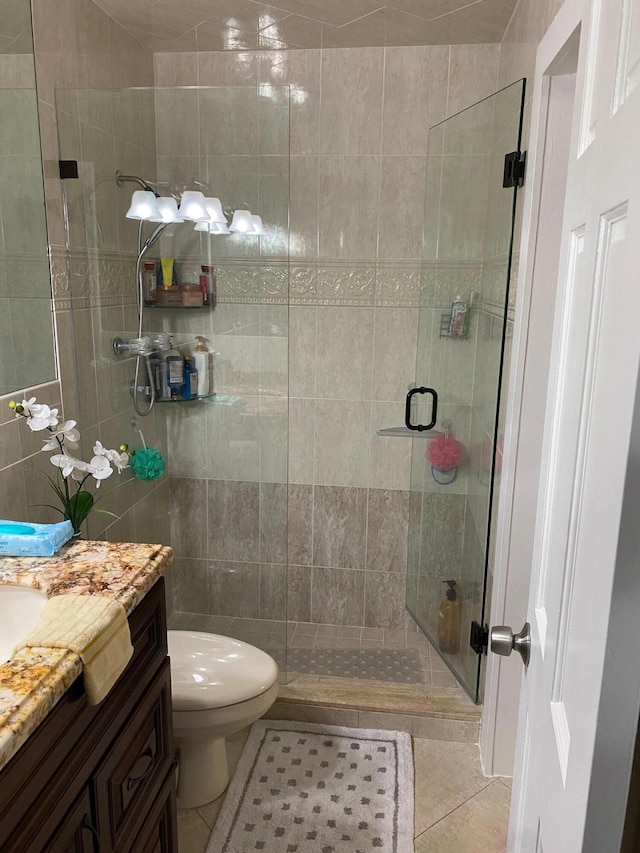 bathroom featuring tile patterned flooring, vanity, toilet, and a shower with shower door