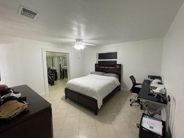 bedroom with ceiling fan, light tile patterned floors, and a textured ceiling