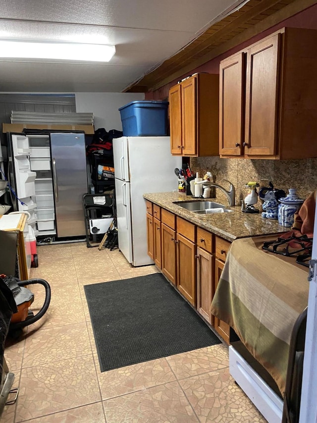 kitchen featuring light stone countertops, sink, tasteful backsplash, white appliances, and light tile patterned flooring