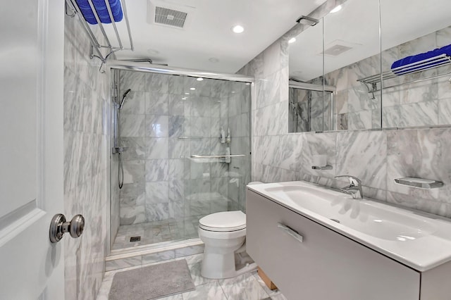 bathroom with vanity, toilet, a shower with door, and tile walls