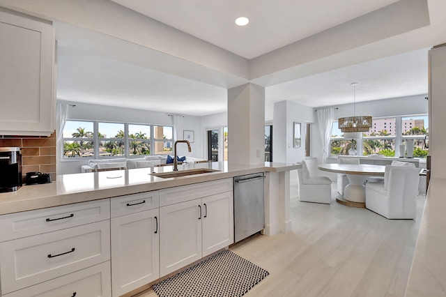 kitchen with white cabinetry, dishwasher, sink, backsplash, and pendant lighting