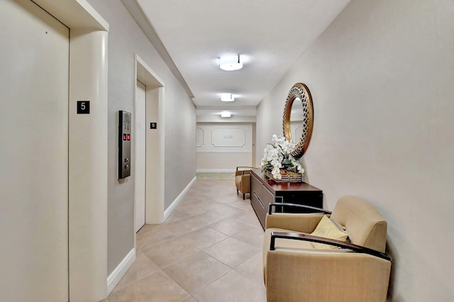 corridor featuring elevator and light tile patterned floors