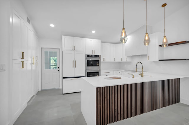 kitchen featuring double oven, kitchen peninsula, hanging light fixtures, sink, and light tile floors