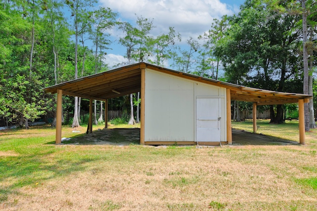 view of outdoor structure with a carport and a yard