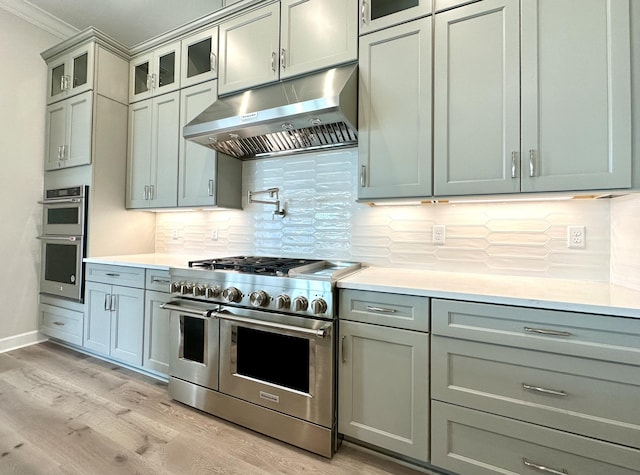 kitchen featuring under cabinet range hood, appliances with stainless steel finishes, gray cabinets, and light wood-style floors