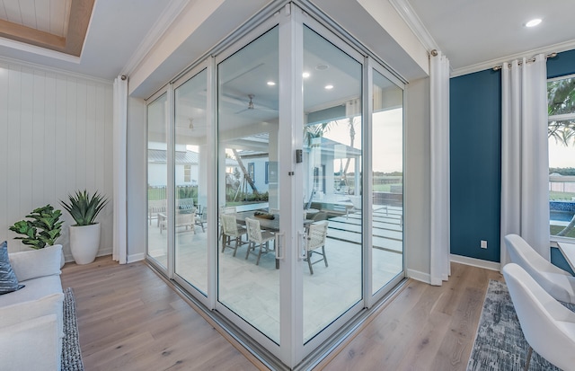 doorway to outside with light wood-type flooring, ceiling fan, and ornamental molding