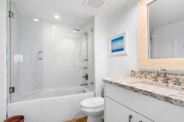 full bathroom with bath / shower combo with glass door, toilet, and vanity