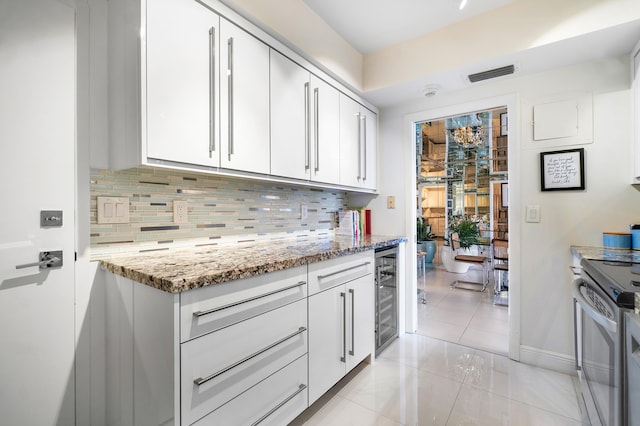 kitchen featuring white cabinets, backsplash, light tile patterned floors, stainless steel electric range oven, and light stone countertops