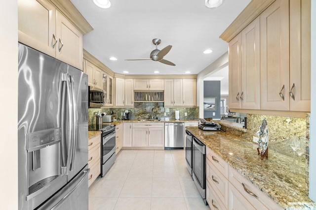 kitchen with decorative backsplash, light tile patterned floors, appliances with stainless steel finishes, light stone counters, and ceiling fan