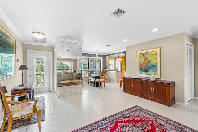 tiled entryway featuring ornamental molding and an inviting chandelier