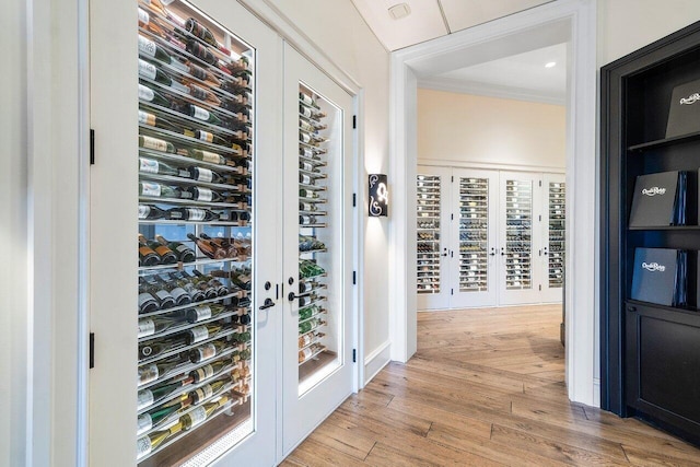 wine area with light hardwood / wood-style floors and crown molding