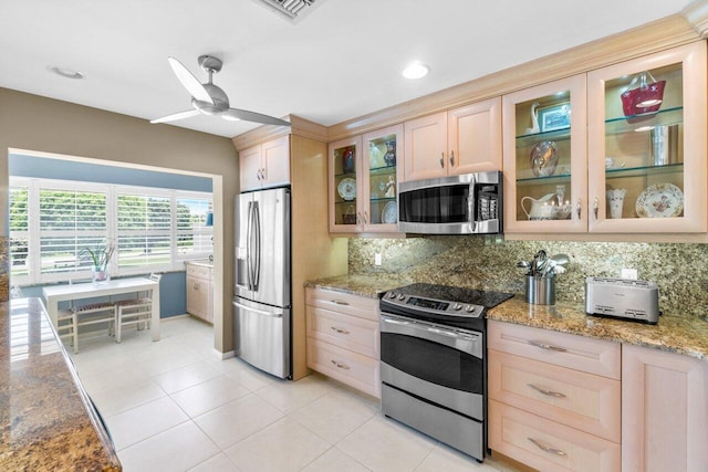 kitchen featuring tasteful backsplash, light brown cabinetry, ceiling fan, stainless steel appliances, and light stone counters