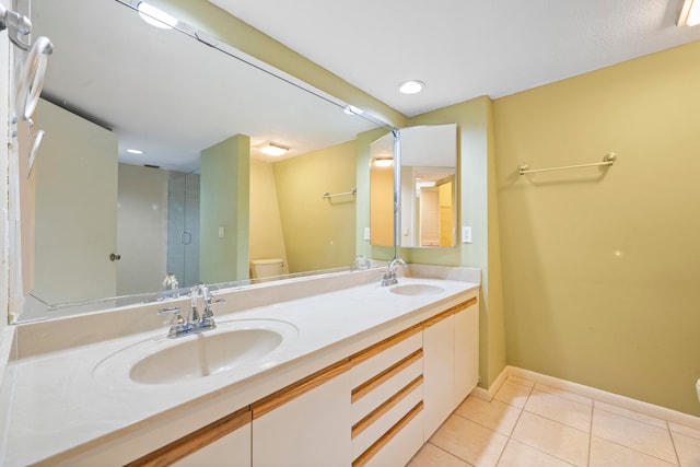 bathroom with vanity with extensive cabinet space, dual sinks, toilet, and tile floors