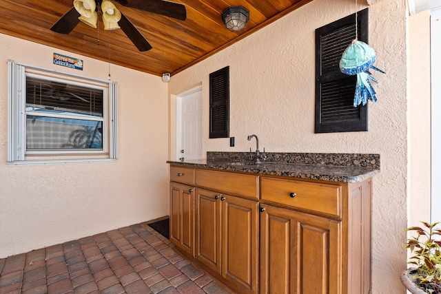 exterior space with dark stone countertops, sink, wood ceiling, ceiling fan, and dark tile floors