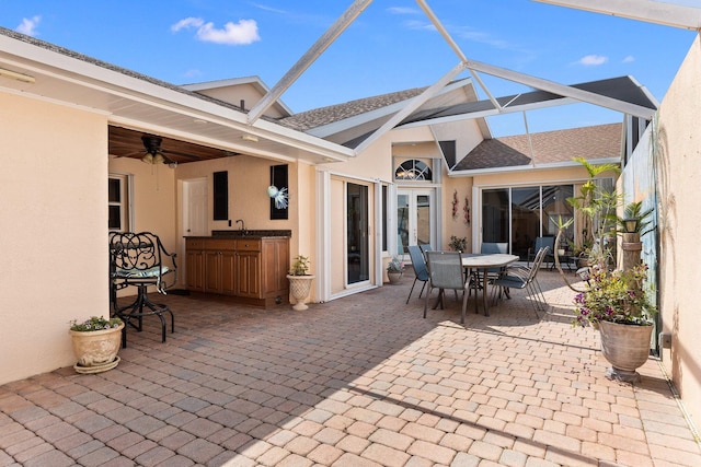 view of patio with ceiling fan, a lanai, and sink