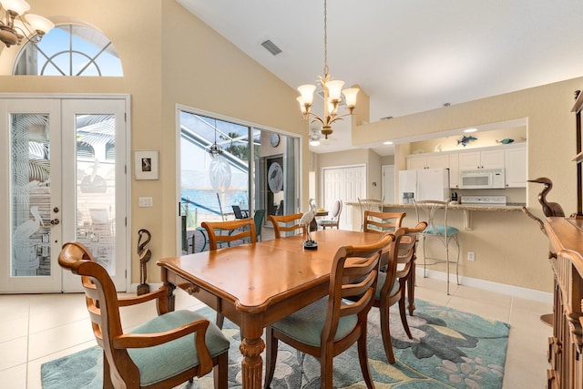 tiled dining space with high vaulted ceiling, an inviting chandelier, and french doors