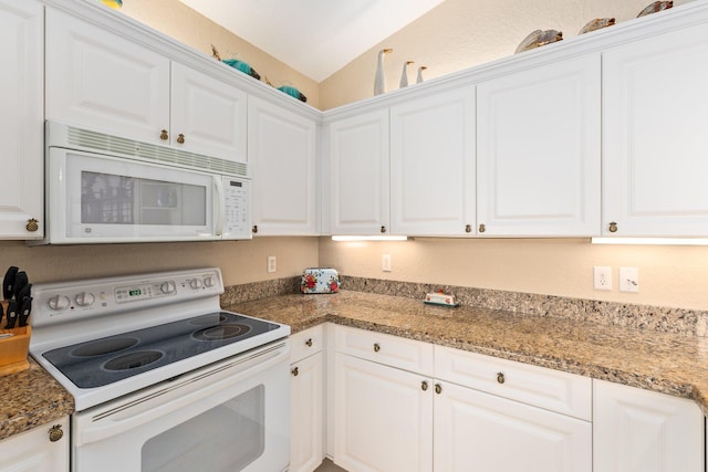 kitchen with white appliances, white cabinets, lofted ceiling, and dark stone counters