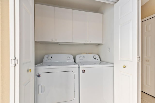 laundry area with independent washer and dryer, cabinets, and light tile floors