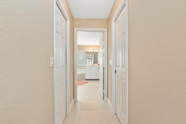 hallway featuring a textured ceiling and light tile floors