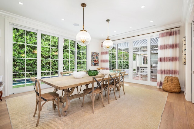 dining space with a healthy amount of sunlight, light wood-type flooring, and crown molding