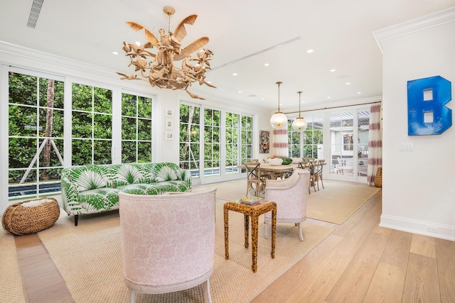 interior space featuring light wood-type flooring, an inviting chandelier, a wealth of natural light, and crown molding