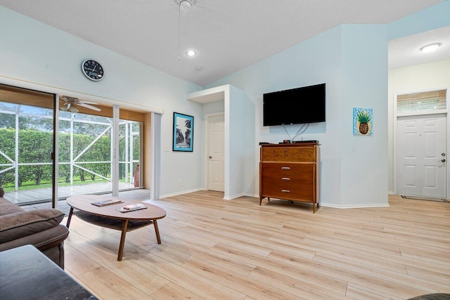 living room featuring light hardwood / wood-style flooring, lofted ceiling, ceiling fan, and a textured ceiling