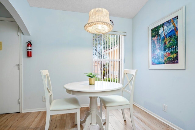 dining space with a textured ceiling and light wood-type flooring