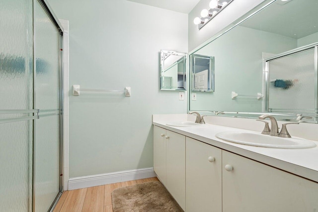 bathroom with wood-type flooring, a shower with door, and vanity