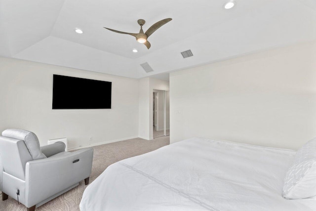 bedroom with ceiling fan, light carpet, and a tray ceiling