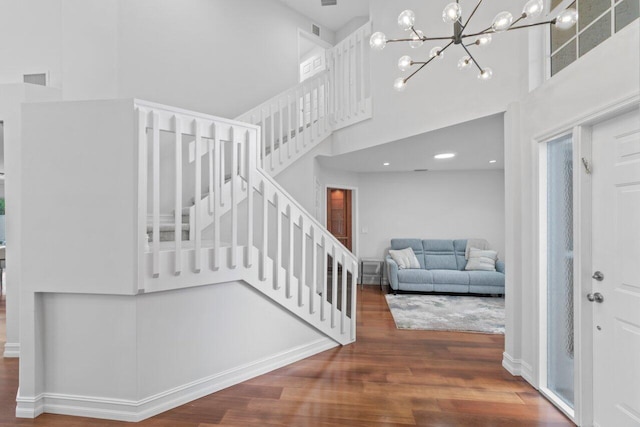 stairway featuring a chandelier, a high ceiling, and hardwood / wood-style flooring