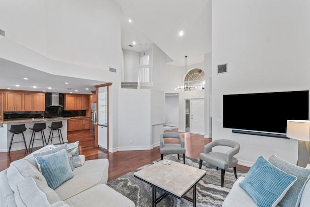 living room featuring a towering ceiling, dark hardwood / wood-style floors, and a notable chandelier