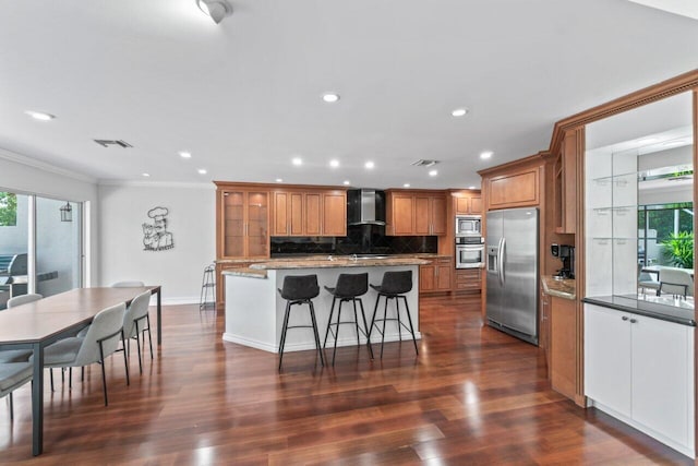 kitchen featuring plenty of natural light, wall chimney exhaust hood, dark wood-type flooring, and appliances with stainless steel finishes