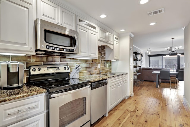 kitchen with sink, light wood-type flooring, a notable chandelier, white cabinetry, and stainless steel appliances