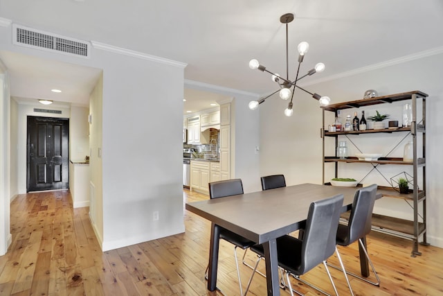 dining area featuring ornamental molding, a notable chandelier, and light wood-type flooring