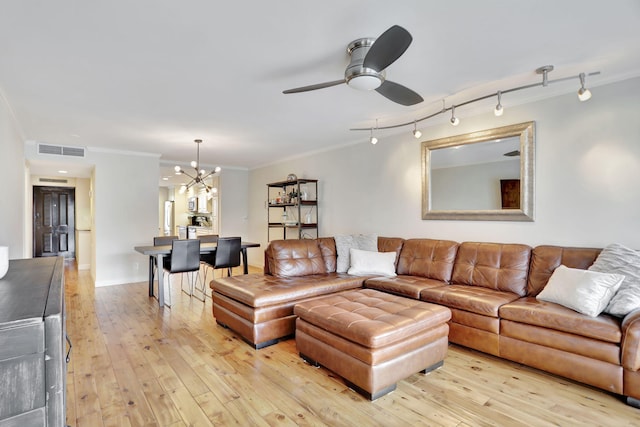 living room with ceiling fan with notable chandelier, light wood-type flooring, and ornamental molding