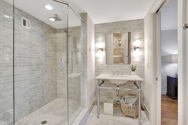 bathroom featuring sink, hardwood / wood-style flooring, a shower with door, and tile walls