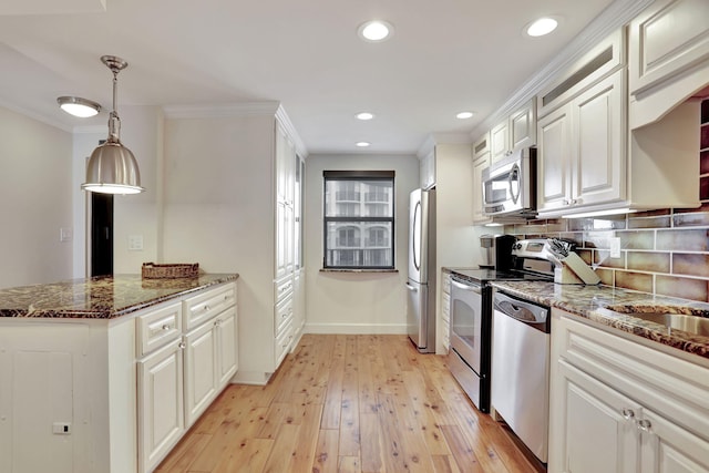 kitchen featuring stainless steel appliances, crown molding, pendant lighting, white cabinets, and light wood-type flooring