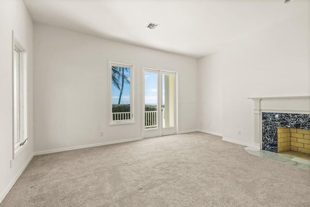 unfurnished living room with baseboards, carpet, visible vents, and a premium fireplace