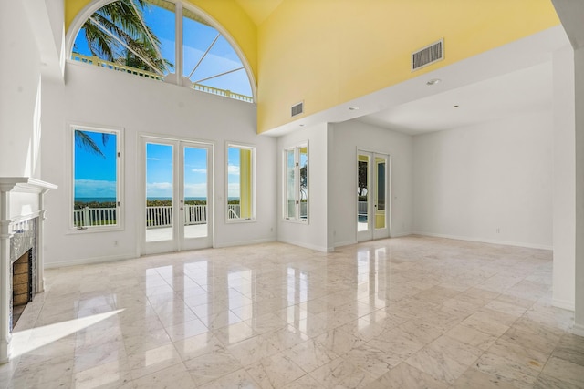 unfurnished living room with a fireplace, french doors, visible vents, and a wealth of natural light