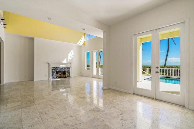 unfurnished living room with plenty of natural light, french doors, marble finish floor, and a high end fireplace