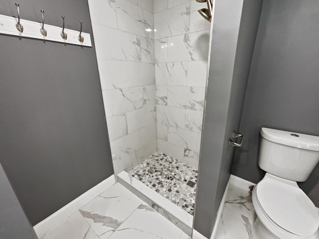 bathroom featuring a tile shower, tile flooring, and toilet