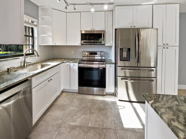 kitchen featuring white cabinetry, dark stone countertops, appliances with stainless steel finishes, sink, and light tile floors