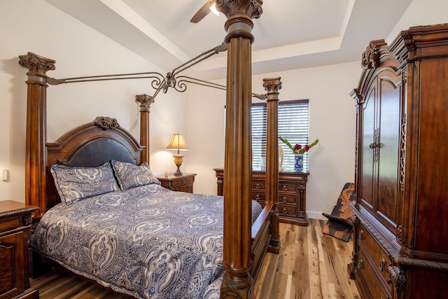 bedroom with ceiling fan, light hardwood / wood-style floors, and a raised ceiling