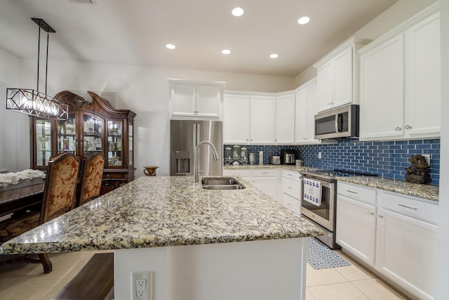 kitchen with a center island with sink, sink, appliances with stainless steel finishes, decorative light fixtures, and white cabinetry