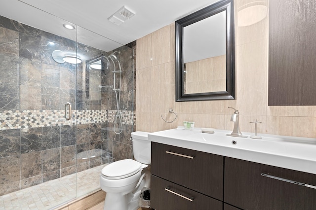 bathroom with walk in shower, vanity, toilet, and tile walls