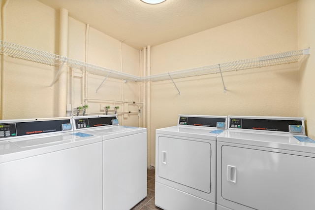 laundry room featuring a textured ceiling, washing machine and dryer, and dark tile patterned floors