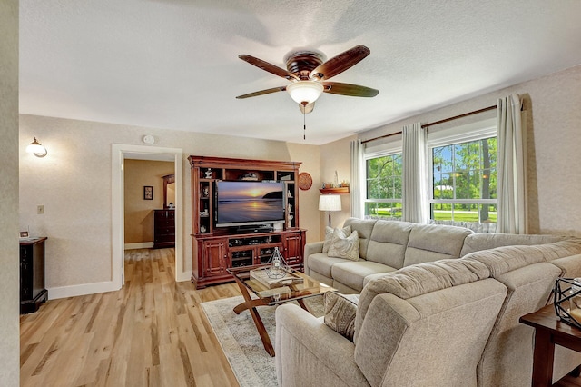 living room featuring ceiling fan, light hardwood / wood-style floors, and a textured ceiling