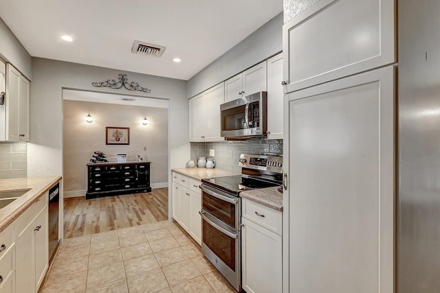 kitchen featuring white cabinets, stainless steel appliances, and light tile patterned floors