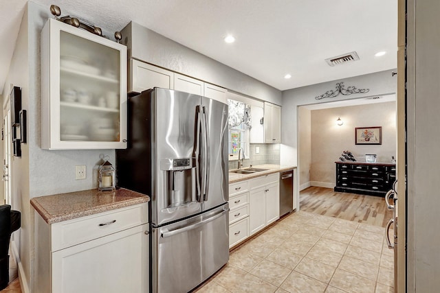 kitchen featuring light stone counters, sink, white cabinets, and stainless steel appliances