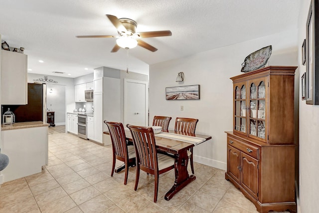 tiled dining area with a textured ceiling and ceiling fan